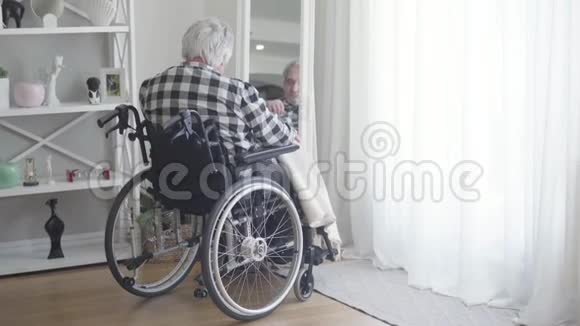 从轮椅上成熟的白人男子的背影看镜子里的倒影悲伤的老年退休人员视频的预览图