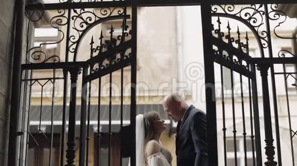 新婚夫妇在老门接吻新郎新娘接吻婚礼视频的预览图