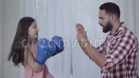 侧视自信的小中东女孩拳击父亲手在室内与父母一起训练漂亮女儿视频的预览图