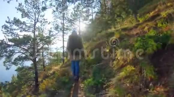 在阳光明媚的日子里一个戴着兜帽背着背包的女孩沿着陡峭的斜坡散步视频的预览图