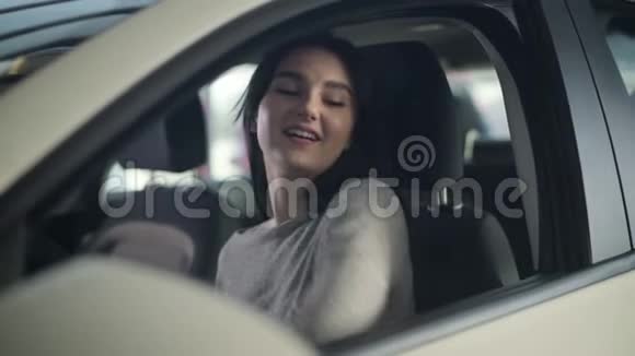 年轻迷人的白种人女人看着镜头坐在司机新车的座位上的肖像快乐成功视频的预览图