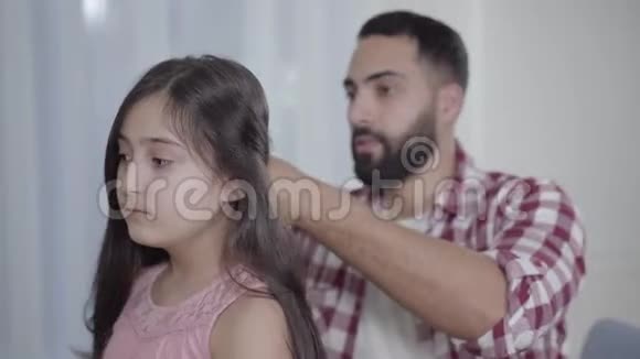 一边看着尴尬的中东男人试图处理女儿头发和叹息年轻的父亲照顾视频的预览图