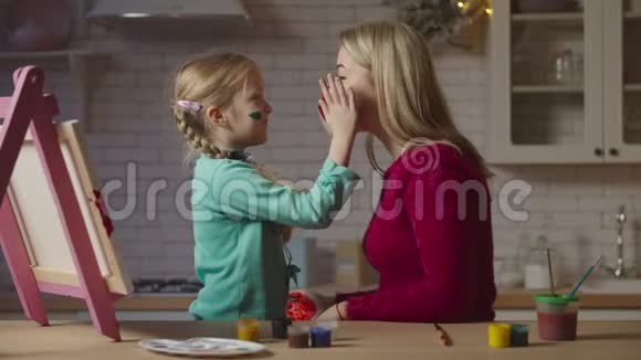 可爱的孩子用颜料涂抹母亲的脸视频的预览图