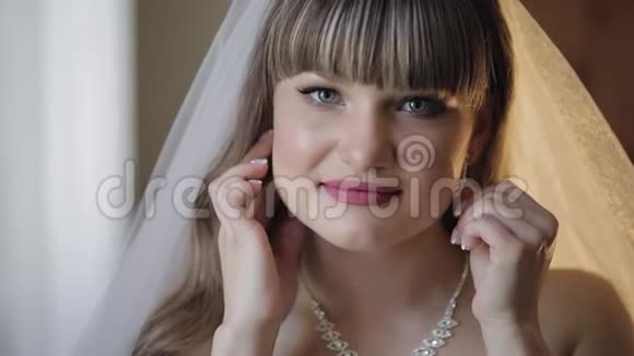 穿着婚纱戴面纱戴耳环的美丽可爱的新娘视频的预览图