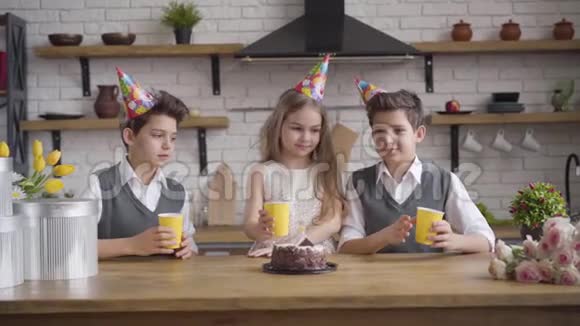 快乐的女孩和两个相同的男孩在生日聚会上碰杯喝茶双胞胎兄弟庆祝节日视频的预览图