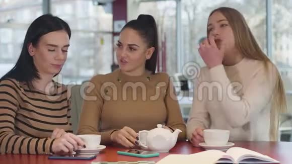三个年轻美丽的白种人女人坐在咖啡馆的桌子旁交谈的肖像可爱的女士在里面休息视频的预览图