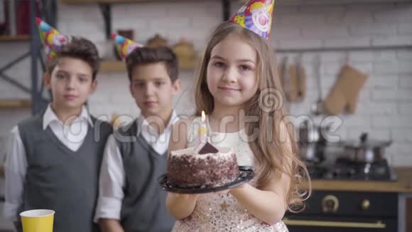 积极的小白种人女孩戴着生日蛋糕和看着相机的肖像她的孪生兄弟视频的预览图