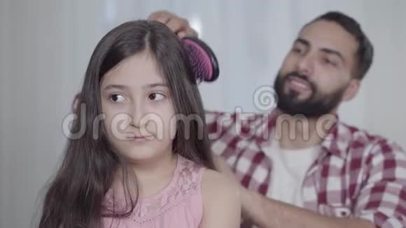 年轻微笑的中东男人梳着长长的黑发的女儿体贴的父亲照顾可爱的小女孩视频的预览图