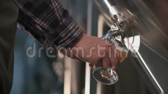 一名男性啤酒商将啤酒从啤酒罐倒入玻璃杯中品尝特写视频的预览图