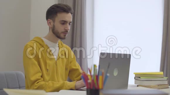自信的白种人年轻男子与笔记本电脑工作打哈欠和把头放在桌子上的肖像累坏了的学生视频的预览图