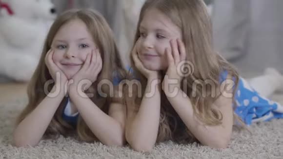一对幸福的白种人双胞胎姐妹互相看着对方转身对着镜头躺着抱着头视频的预览图