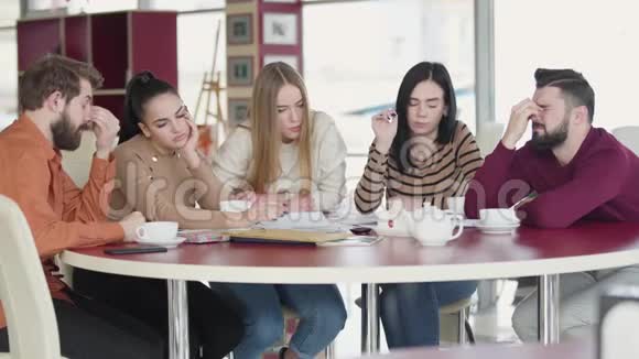 一群疲惫的白种人成年学生坐在桌子旁交谈年轻大学生一起学习视频的预览图
