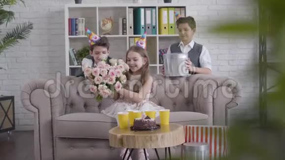 长镜头两个时髦的孪生兄弟送花束和礼物给快乐的黑发白种人女孩漂亮的妹妹视频的预览图