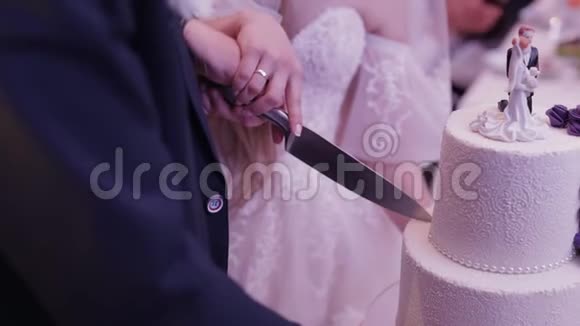 新郎新娘正在切婚礼蛋糕双手切一块蛋糕视频的预览图
