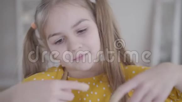 为面包店从手指上品尝甜混合物的快乐小女孩特写微笑可爱的白种人儿童烘焙视频的预览图