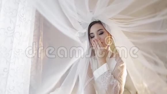 美丽可爱的新娘在面纱下穿着睡衣婚礼日视频的预览图