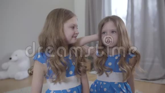 快乐和悲伤的白种人双胞胎在室内交谈家庭中快乐的女孩和烦恼的孩子的肖像差异视频的预览图