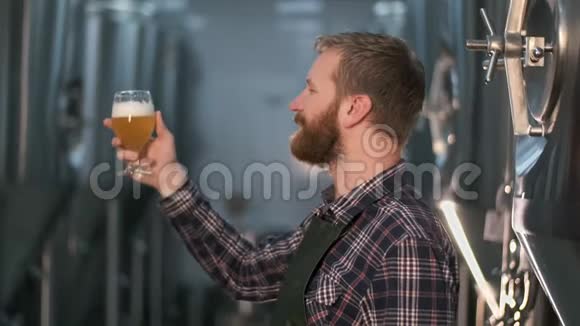 有胡子的成功商人啤酒厂站在里面时要检查啤酒罐里新酿啤酒的质量视频的预览图