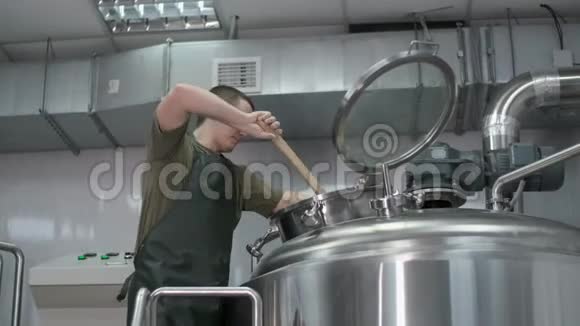 工人男酿酒工在啤酒罐里搅拌啤酒混合物视频的预览图