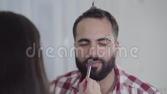 面目全非的小女孩在英俊开朗的中东男人脸上化妆快乐的父亲视频的预览图