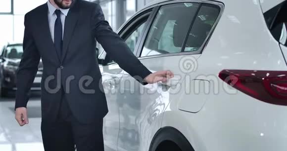 专业司机为成功的成年金发女商人打开车门带着购物袋成功视频的预览图
