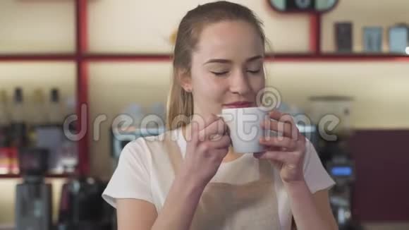 微笑的白种人女人闻咖啡的特写镜头年轻的女服务员在咖啡馆里享受早晨的卡布奇诺幸福快乐视频的预览图