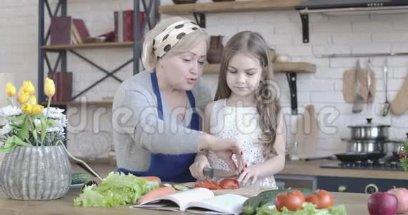 积极白种人奶奶教孙女切番茄一个深褐色头发的小女孩在帮一个老女人视频的预览图