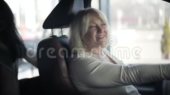 一位年长的金发白种人女人在新汽车里环顾四周她年轻漂亮的女儿坐在后面视频的预览图