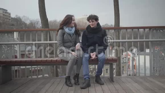 白人青年男女坐在城市公园的长凳上说话的肖像快乐的青少年学生视频的预览图