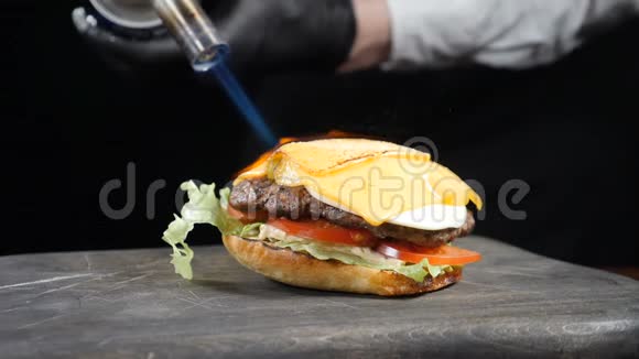 厨师用火炬在美味的汉堡上燃烧奶酪烧火炉煮制芝士片视频的预览图