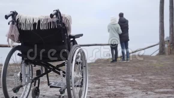 特写轮椅两个模糊的人在后台交谈白种人男人和女人享受秋日视频的预览图