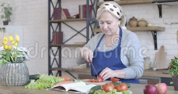 现代厨房切番茄的浓缩高级女性肖像积极的中年白种人退休人员准备视频的预览图