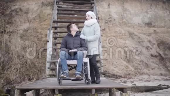坐在轮椅上的残疾少年和成年女子微笑着向一边看着对方的画像视频的预览图