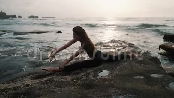 女人在海滩上做伸展运动在背景上做海洋慢动作视频的预览图