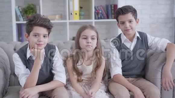 快乐可爱的白种人女孩看着两边坐着的双胞胎兄弟用手给他们戴上角有趣搞笑视频的预览图