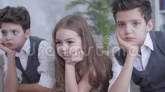 一个棕色皮肤的漂亮女孩的特写镜头她和双胞胎兄弟坐在沙发上手牵着头肖像视频的预览图