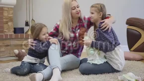 快乐的白人金发女人拥抱和亲吻女儿的肖像在室内照顾孩子的年轻母亲视频的预览图