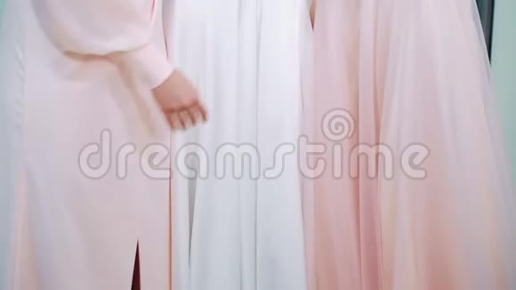 穿着婚纱的微笑新娘在室内拥抱穿着粉色礼服的伴娘视频的预览图
