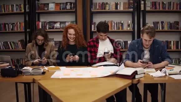 四组大学生两名男性两名女性在休息和使用时一起坐在桌子旁视频的预览图