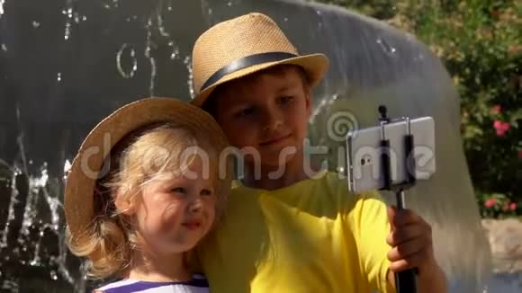 小男孩和小女孩在喷泉背景下在智能手机上自拍视频的预览图