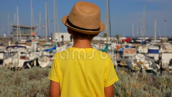 戴帽子的小男孩正看着游艇码头视频的预览图