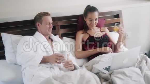 一对夫妇早上躺在床上男人和女人喝咖啡和果汁视频的预览图