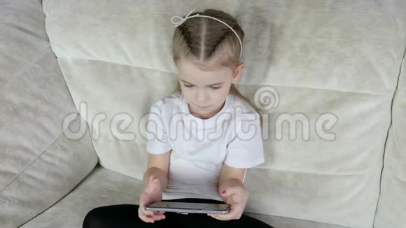 有趣的小女孩在家玩智能手机视频的预览图