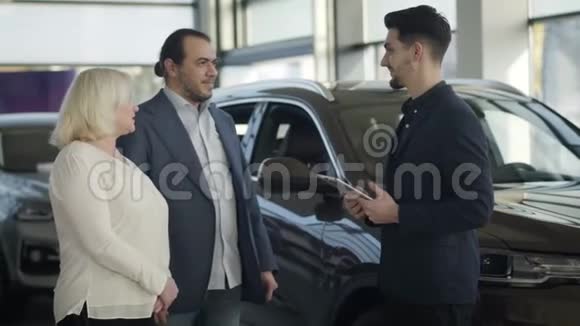 年轻的白种人汽车经销商问候经销商的访客成功的商人适合为他买新车视频的预览图