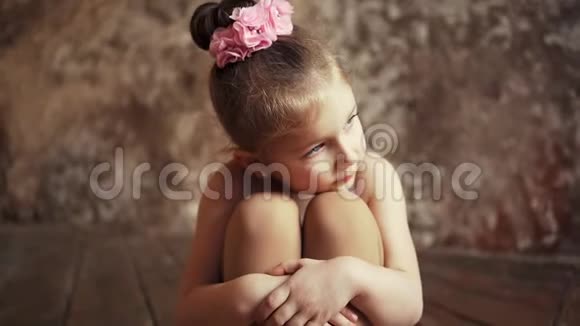 悲伤的小可爱的女婴头上戴着蝴蝶结盘腿坐在地板上慢动作在安定区射击视频的预览图