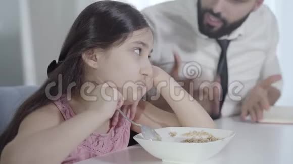模糊的中东年轻人对悲伤的小女孩大喊大叫把粥和勺子混合在一起匆忙父亲的画像视频的预览图