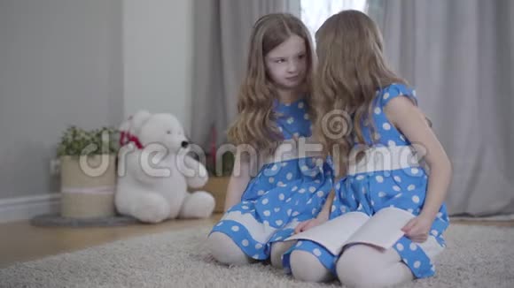 快乐的白种人女孩的肖像分散了双胞胎姐妹的阅读快乐的兄弟姐妹一起在家休息视频的预览图