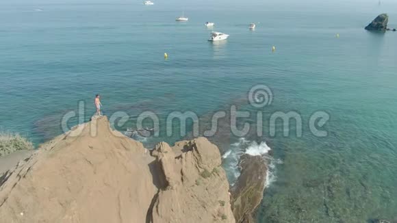 空中射击一名男子站在透明的海面上的悬崖上视频的预览图