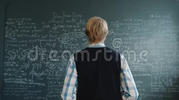 穿休闲服装的聪明人走到黑板前写公式的画像视频的预览图