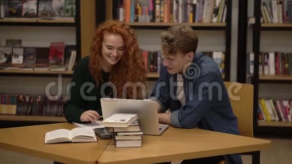 两位年轻学生的正面景色一位穿着黑色毛衣的红色长发另一位穿着蓝色衬衫的男生在交谈视频的预览图